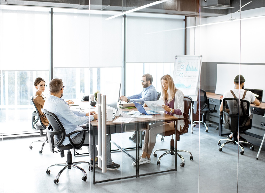 Caledonia, MN - Group of Professionals Sitting Together in a Glass Office