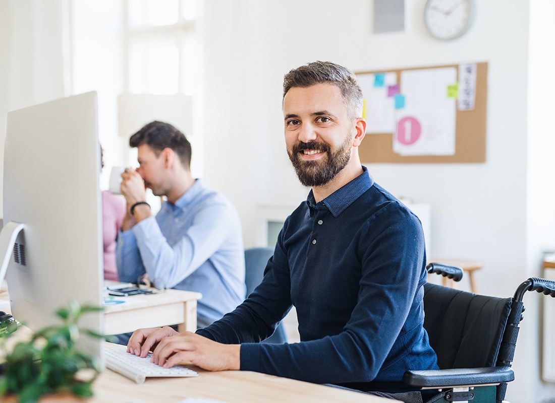 Le Sueur, MN - Young Businessman in Wheelchair With Colleagues Working in a Modern Office