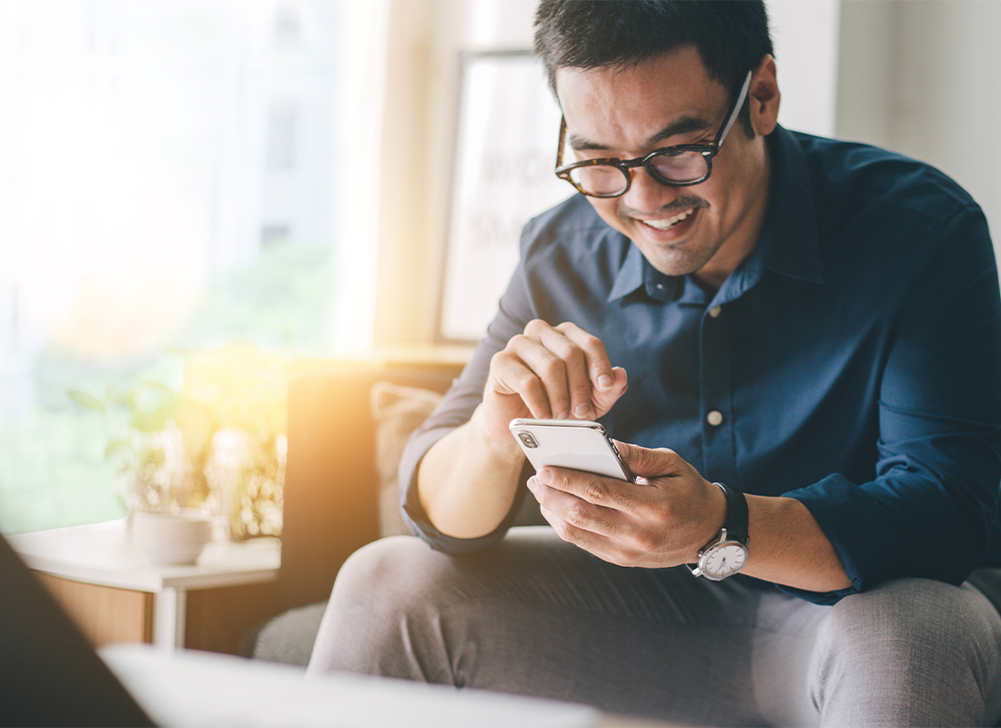 Quarterly Online Magazine - Young Man Looking at Phone With a Smile on His Face